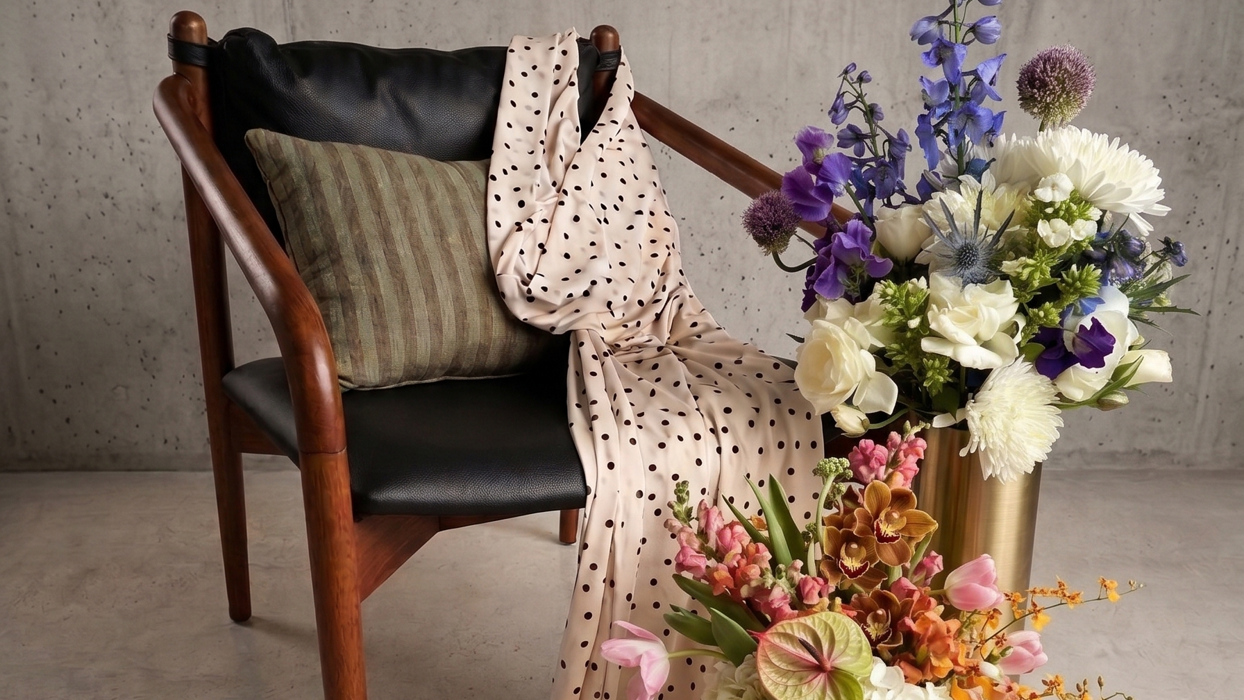 Beige polka dot fabric draped over a chair with floral arrangements on a concrete floor.